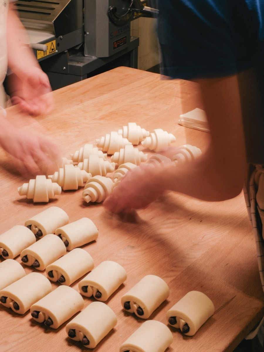 Bakers hand-shaping laminated croissants and pain au chocolat at Santo Bakehouse, Malasaña Madrid